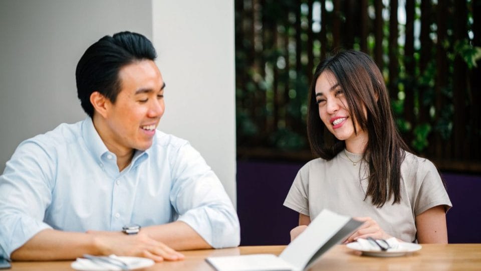 male and a female laughing while having a conversation