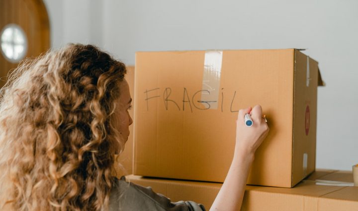 A Girl Writing The Word 'fragile' On A Box